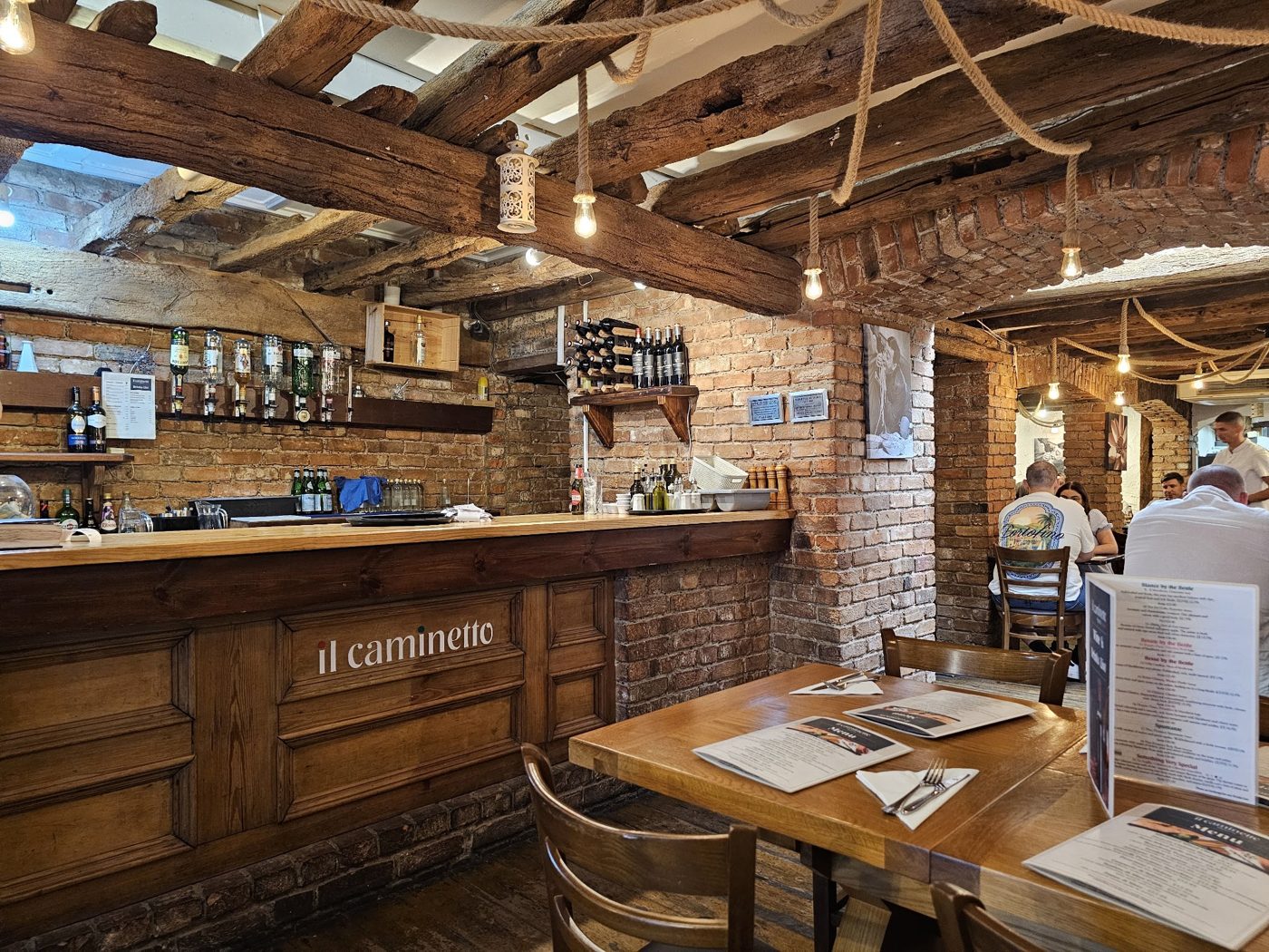 Inside IL CAMINETTO: the bar and the beamed dining room